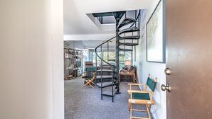 Una escalera de caracol en una habitación con un escritorio, sillas y una estantería.