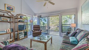 Un salón amplio con una mesa de centro de cristal, un sillón de cuero, un sofá estampado y una estantería.