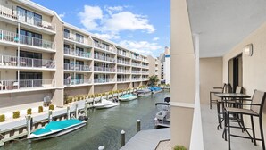 A hotel with multiple balconies, a marina with boats, and outdoor seating. - Wight Bay 254 by Seaside Vacations & Sales (Ocean City)