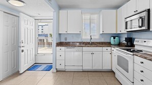 A modern kitchen with white cabinets, a granite countertop, a built-in oven, and a microwave. - Wight Bay 254 by Seaside Vacations & Sales (Ocean City)