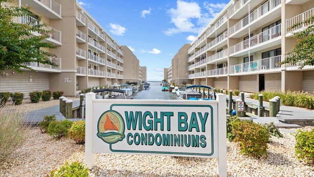 A sign for Wight Bay Condominiums with a view of the marina and condominiums. - Wight Bay 254 by Seaside Vacations & Sales (Ocean City)