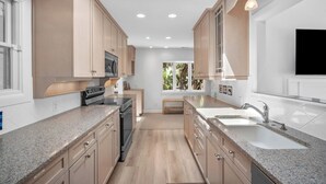 A modern kitchen with granite countertops, stainless steel appliances, and wooden cabinets. - Gorgeous Sunsets and Marsh Views, Pet Friendly, Golf Cart Included (Fripp Island)