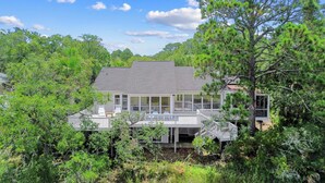 A house surrounded by dense greenery, with a covered porch and a visible deck area. - Gorgeous Sunsets and Marsh Views, Pet Friendly, Golf Cart Included (Fripp Island)