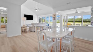A spacious living area with a dining table, chairs, and a ceiling fan. - Gorgeous Sunsets and Marsh Views, Pet Friendly, Golf Cart Included (Fripp Island)