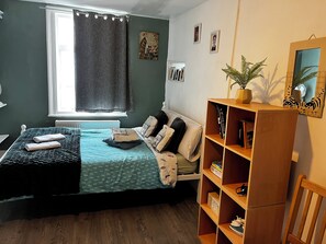 Ein Schlafzimmer mit einem Bett, einem Holzregal, einem Heizkörper und einem Fenster mit Vorhängen.