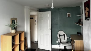 A room with a white door, a desk, a chair, a bookshelf, and a potted plant. - 2 Bedroom Basit Flat in Center. (London)