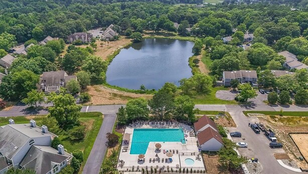 An aerial view of a residential area with a large lake surrounded by houses, a swimming pool, and a tennis court. - One bedroom Apartment in Rehoboth Beach (Rehoboth Beach)