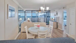 Ein modernes Wohnzimmer mit Glaswand, einem runden Esstisch und einem Deckenventilator.