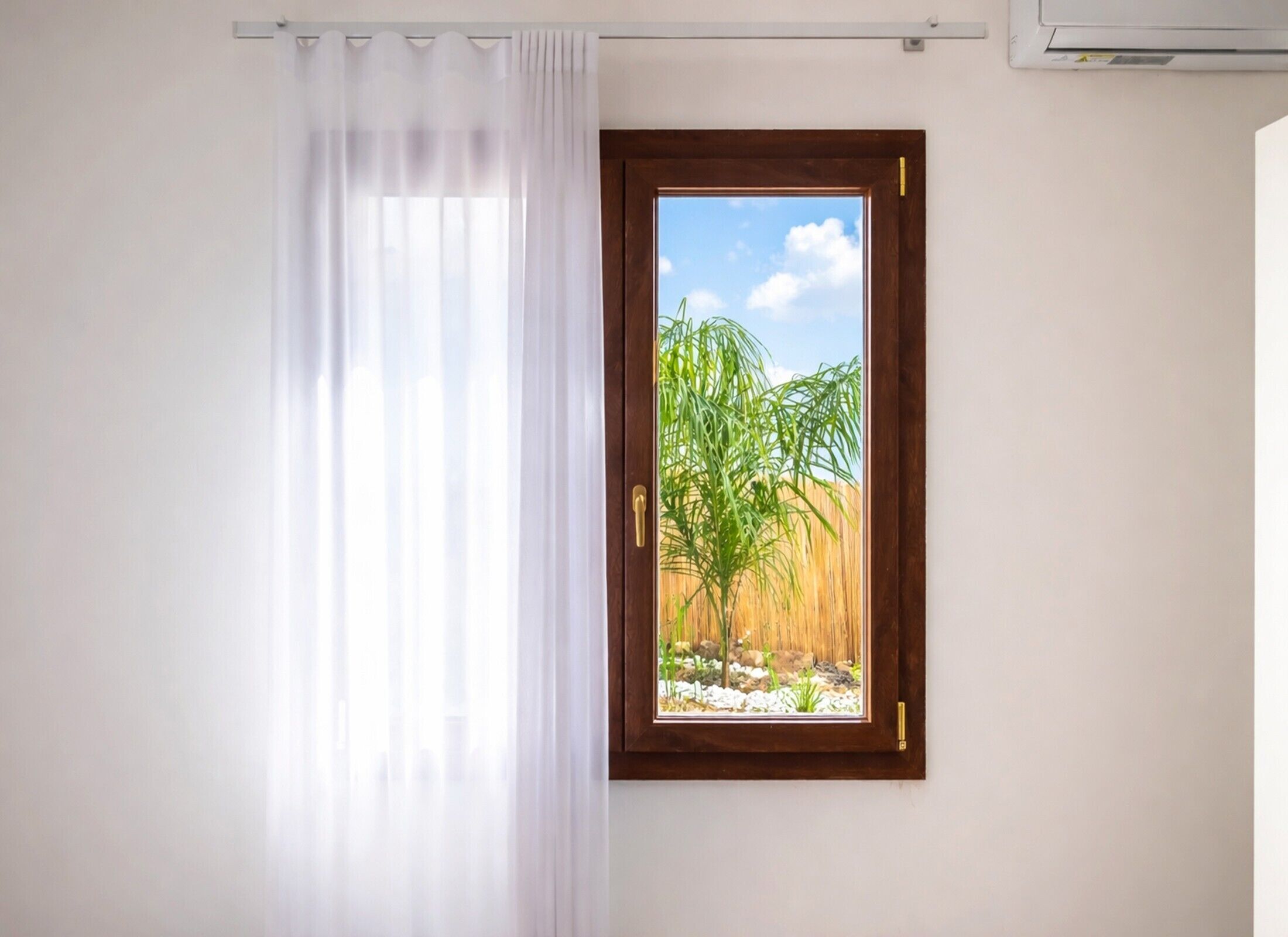 Ein Zimmer mit Fenster, Vorhang und Klimaanlage.