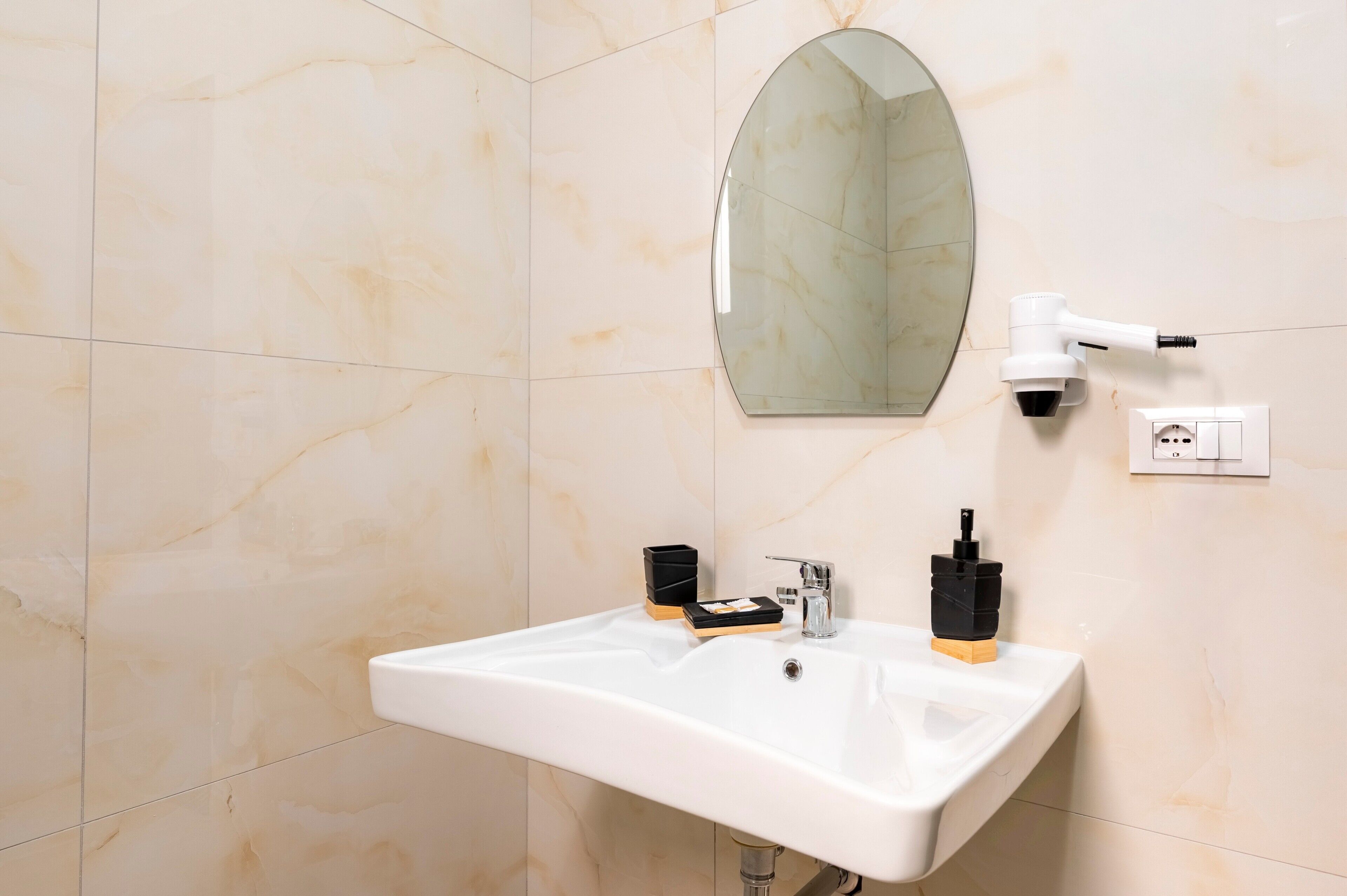 Un baño con lavamanos blanco, un espejo, dispensador de toallas y dispensador de jabón.