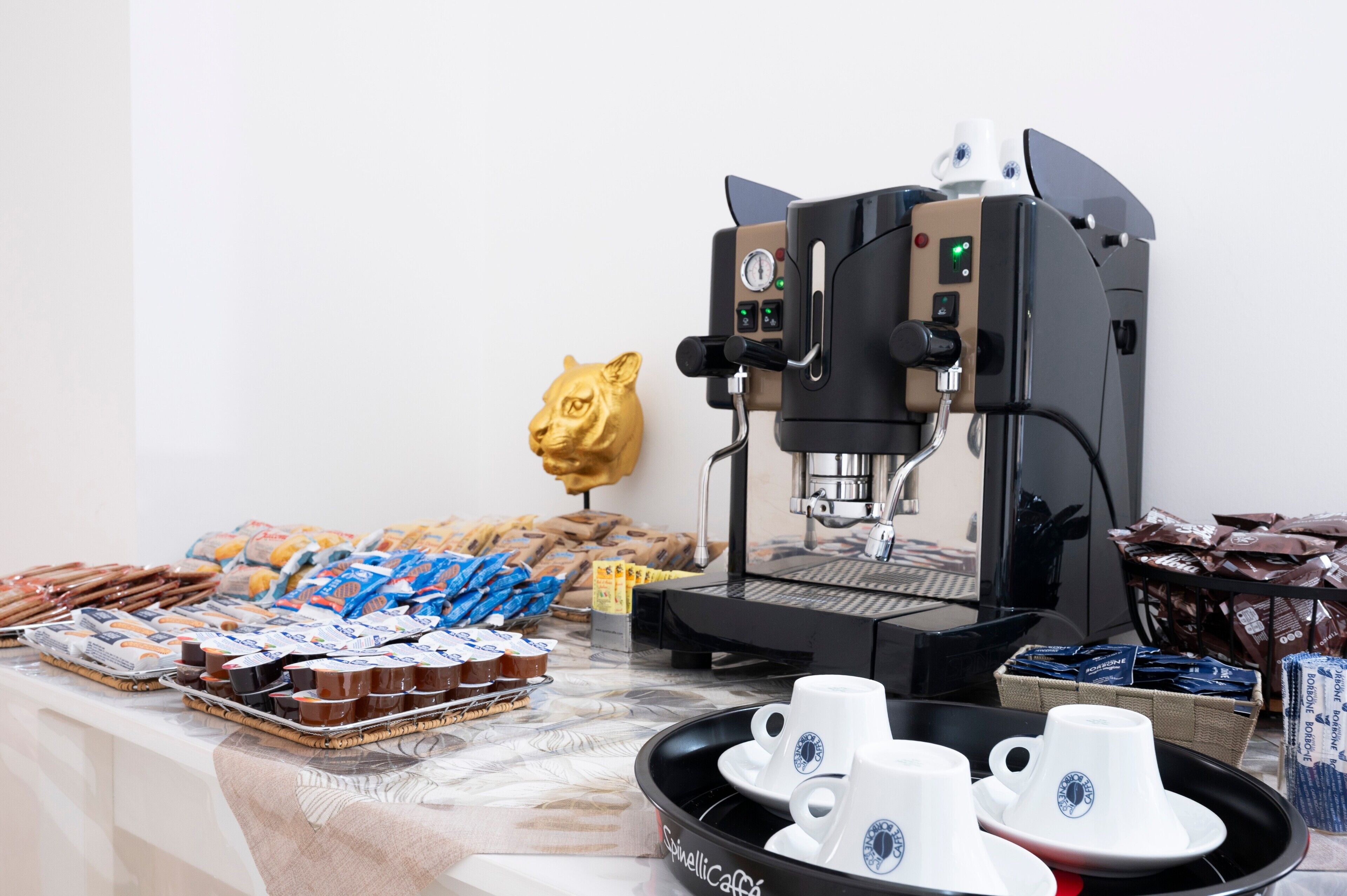 Une machine à café, des pâtisseries et des tasses à café sont posés sur une table.