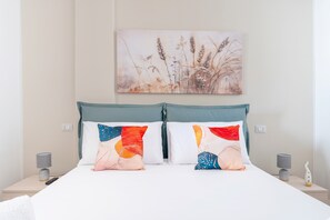 Un lit avec deux oreillers, un tableau accroché au mur et des lampes de chevet.