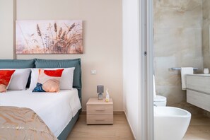 Un dormitorio con cama, mesita de noche y baño con inodoro y lavabo.