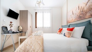 Une chambre à coucher moderne avec un lit, un bureau, une chaise, un téléviseur et un tableau au mur.