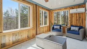 Una habitación con paneles de madera, ventanas amplias, muebles de mimbre y un ventilador de techo.
