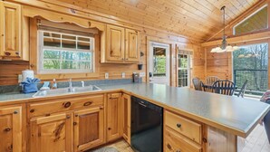 Cocina de cabaña de madera con una isla grande, armarios de madera y lavavajillas.