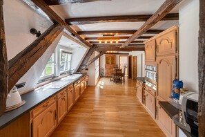 Une cuisine avec des meubles de rangement en bois, un long plan de travail et une vue sur l’extérieur par une fenêtre.