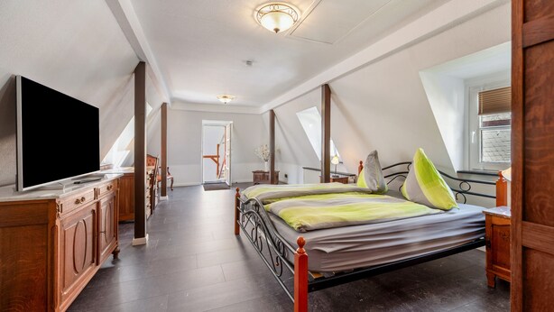 Une chambre à coucher avec un grand lit, une télévision et une commode en bois.
