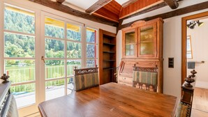 Une pièce dotée d’une grande table en bois, d’un meuble avec des portes en verre et offrant une vue sur un lac par de grandes fenêtres.