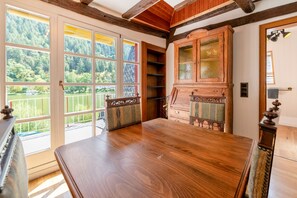 Ein Zimmer mit einem großen Holztisch, einer Vitrine mit Glastüren und Seeblick durch große Fenster.