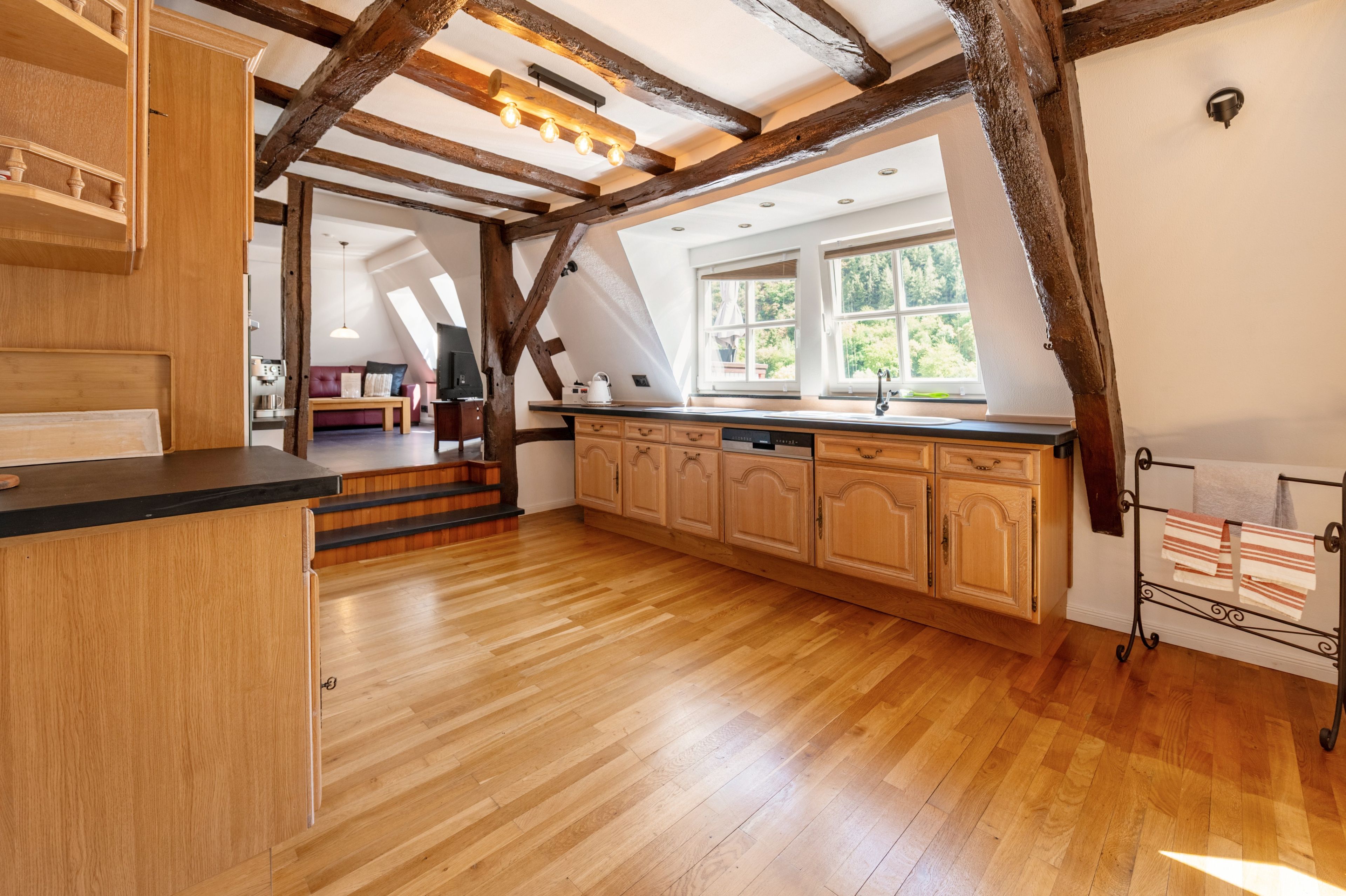Une cuisine spacieuse dotée de meubles en bois, d’un îlot central et offrant une vue sur l’extérieur grâce à de grandes fenêtres.