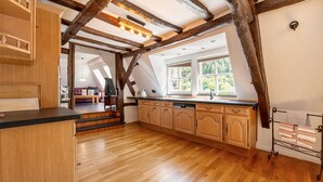 Une cuisine spacieuse dotée de meubles en bois, d’un îlot central et offrant une vue sur l’extérieur grâce à de grandes fenêtres.
