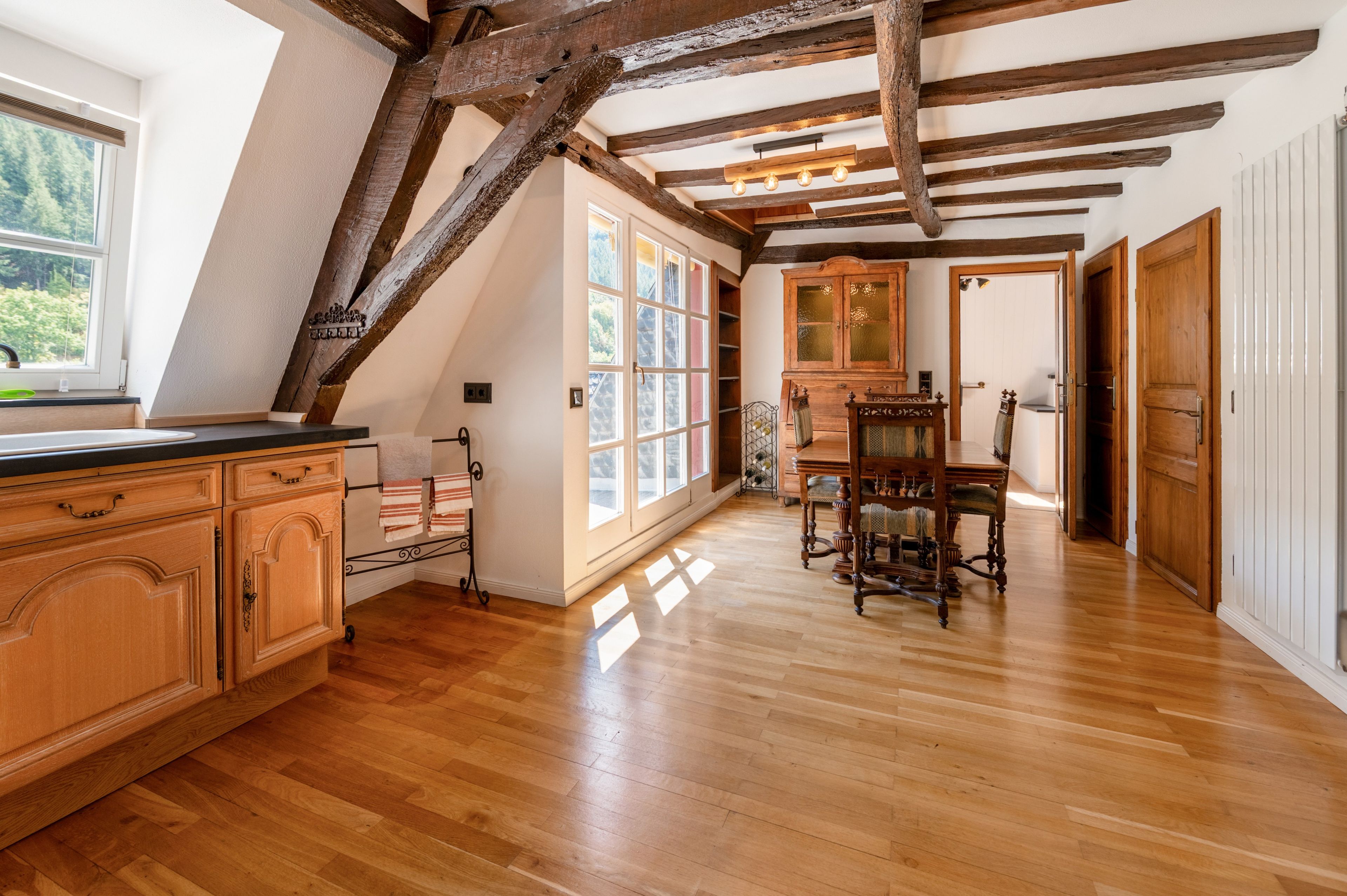 Ein Zimmer mit Holzböden, einem Esstisch und einer Küchenzeile mit Holzschränken.