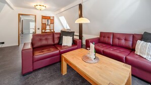 Un salon moderne avec deux canapés en cuir rouge, une table basse en bois et un luminaire suspendu.