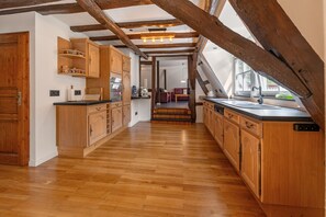 Une cuisine avec des meubles de rangement en bois, un plan de travail et une vue sur l’espace repas.