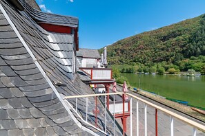 Ein Gebäude mit einem geneigten Dach, einem Balkon mit Geländer und Blick auf einen See mit Booten.