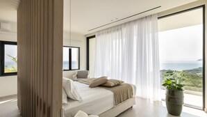 Une chambre moderne avec un grand lit, une vue sur la mer et une plante en pot.