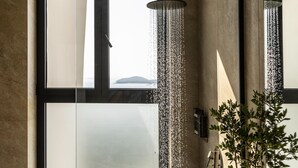 Une salle de bain moderne avec une grande fenêtre, une douche et une plante en pot.