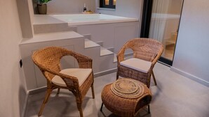 Ett modernt badrum med en stor tvättställ, två fåtöljer i rotting och en liten, rund pall.
