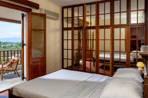 A room with a balcony, a bed, a wooden partition, and a view of the outdoors. - Villa Annelies Pelion (Kato Lechonia)