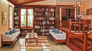 Un accogliente soggiorno con una scala in legno, una grande libreria e un'area salotto confortevole.