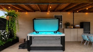 Ein Whirlpool mit Treppe, umgeben von Pflanzen und einer Holzterrasse.