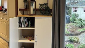 Esquina de una habitación con un armario blanco, un reloj en la pared y vistas a un jardín a través de una ventana.