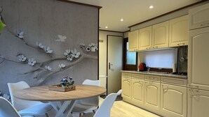 Una cocina moderna con armarios blancos, una mesa de comedor de madera y sillas blancas.
