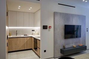 A modern kitchen with wooden cabinets, a built-in dishwasher, and a large flat-screen TV mounted on the wall.
