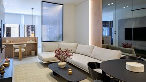 A modern living room with a sofa, coffee table, and a dining area. - Executive Apartment by Fasma Suites (Pireas)