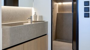 A modern bathroom with a built-in shower, a large mirror, and a vanity with a countertop. - Executive Apartment by Fasma Suites (Pireas)