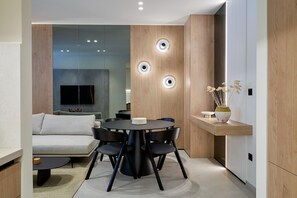 A modern living room with a round dining table, black chairs, a sofa, and a TV.