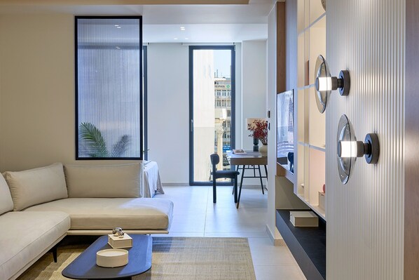 A modern living room with a sofa, a coffee table, and a dining area with a chair and table.