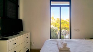 A bedroom with a bed, a TV on a dresser, and a balcony with a view of trees and buildings. - Nitsana Cachemire in Tel Aviv-Yafo (Tel Aviv-Yafo)