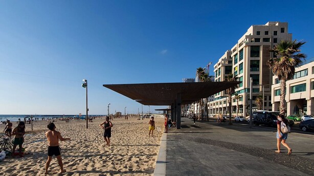 A beach with people, a covered walkway, and buildings in the background. - Nitsana Cachemire in Tel Aviv-Yafo (Tel Aviv-Yafo)