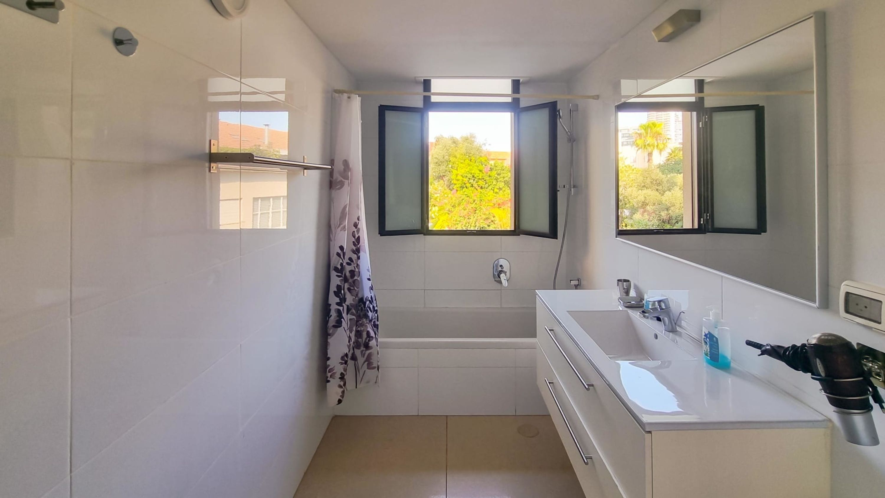 A modern bathroom with a bathtub, a sink, and a large mirror.
