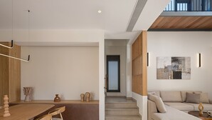 Un soggiorno moderno con zona pranzo, divano e scala che conduce a un livello superiore.