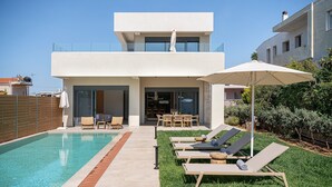 Una casa moderna con piscina, area salotto esterna e giardino curato.