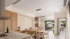 Una cucina moderna con mobili in legno, un'isola centrale e un'area pranzo con sedie e tavolo in legno.