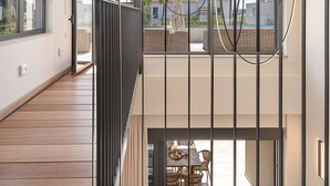 Un interno moderno con pavimento in legno, un balcone con mobili in vimini e vista sulla città.